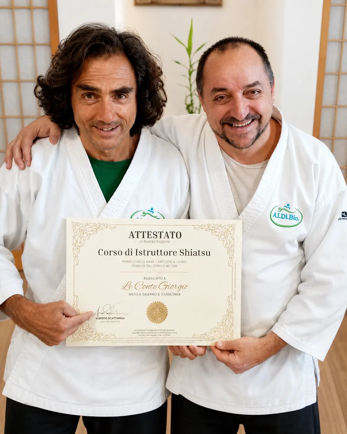 Due operatori Shiatsu A.I.DI.Bio. sorridono in dojo mostrando un attestato di partecipazione al Corso di Istruttore Shiatsu.